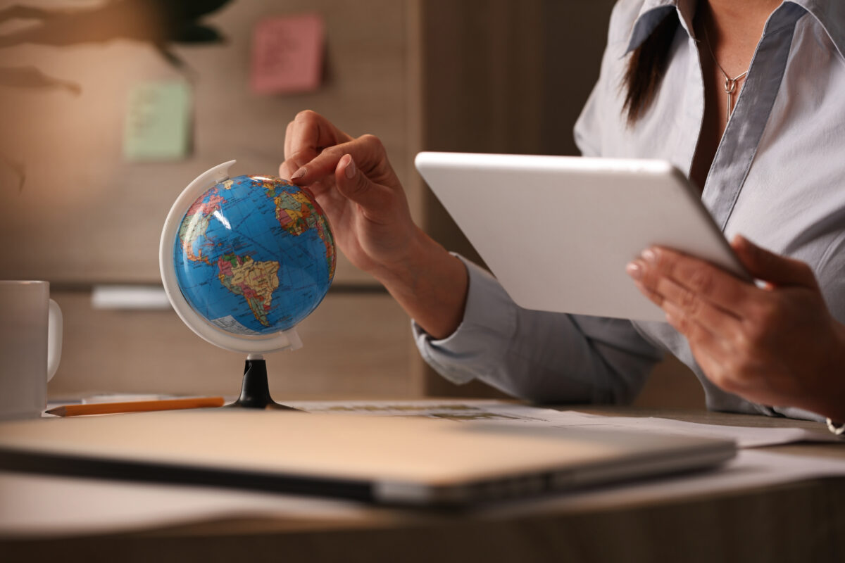 businesswoman using digital tablet while examining globe and planning her vacation.Concept image for how South Africans can land overseas jobs